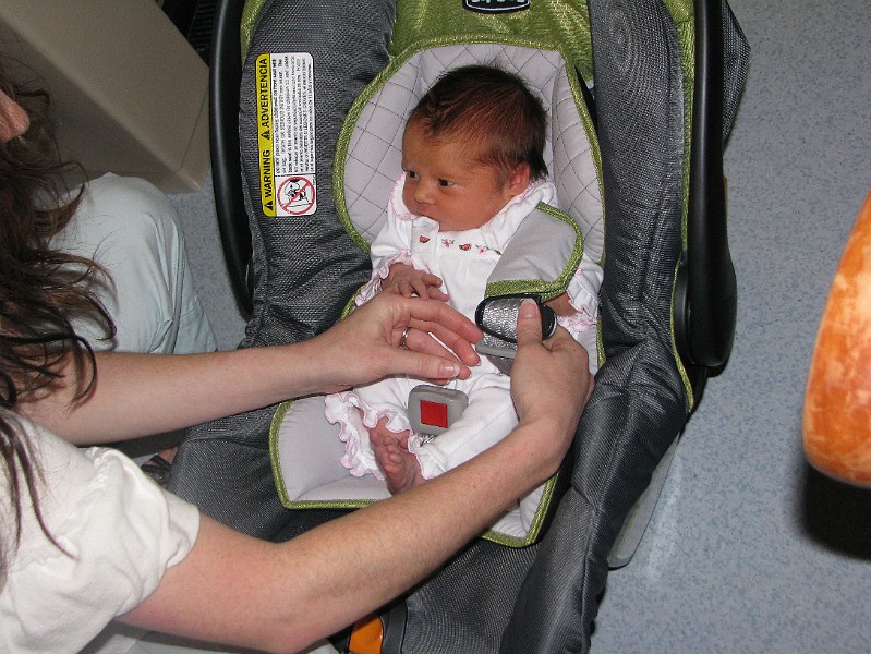 IMG_0543.JPG - Mommy packs me into my carseat. Look at my going-home outfit. It had flowers and watermelons on it.